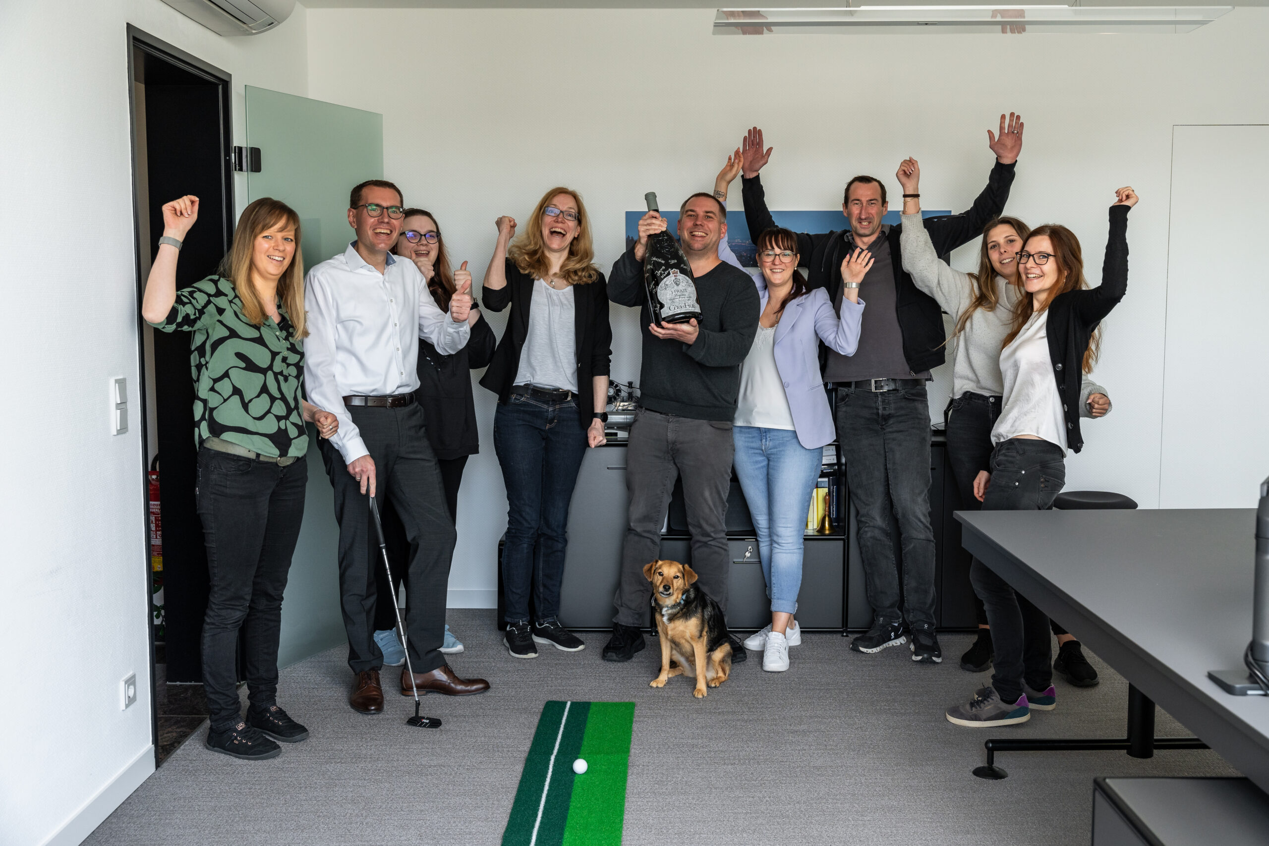 Mitarbeitende der Steuerberatungsgesellschaft Pauly in Kronberg feiern gemeinsam im Buero mit einem Hund